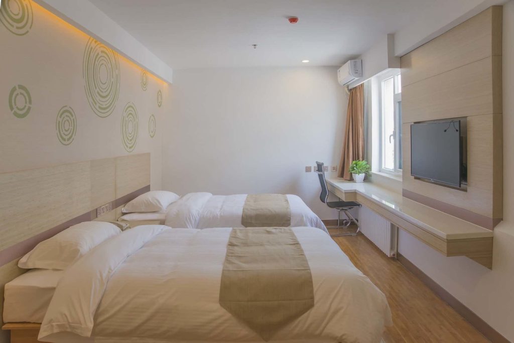 Helles Schlafzimmer mit zwei Betten und einem Fernseher
